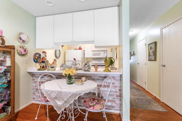 4714 Athalia Dr Unit 26B, Columbus, OH 43228 - kitchen featuring white appliances, white cabinets, wood finished floors, a textured ceiling, and baseboards