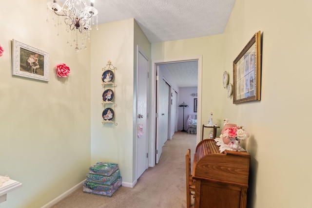 4714 Athalia Dr Unit 26B, Columbus, OH 43228 - hallway featuring light carpet, a textured ceiling, a chandelier, and baseboards
