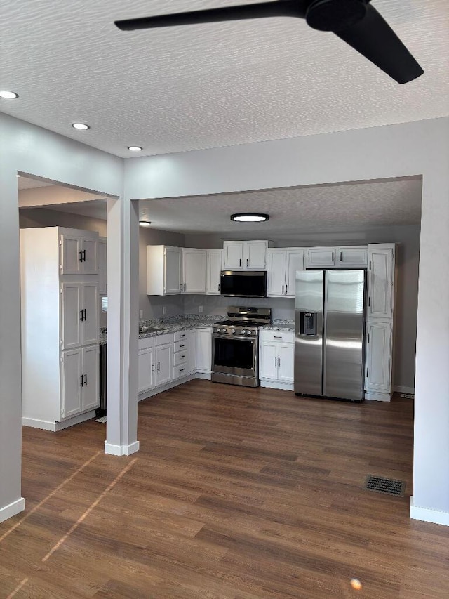 418 Clinton St, Circleville, OH 43113 - kitchen featuring appliances with stainless steel finishes, baseboards, dark wood-style flooring, white cabinetry, and a textured ceiling