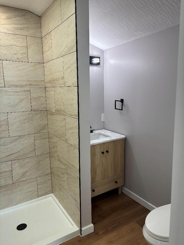 418 Clinton St, Circleville, OH 43113 - bathroom featuring vanity, wood finished floors, toilet, baseboards, and tiled shower