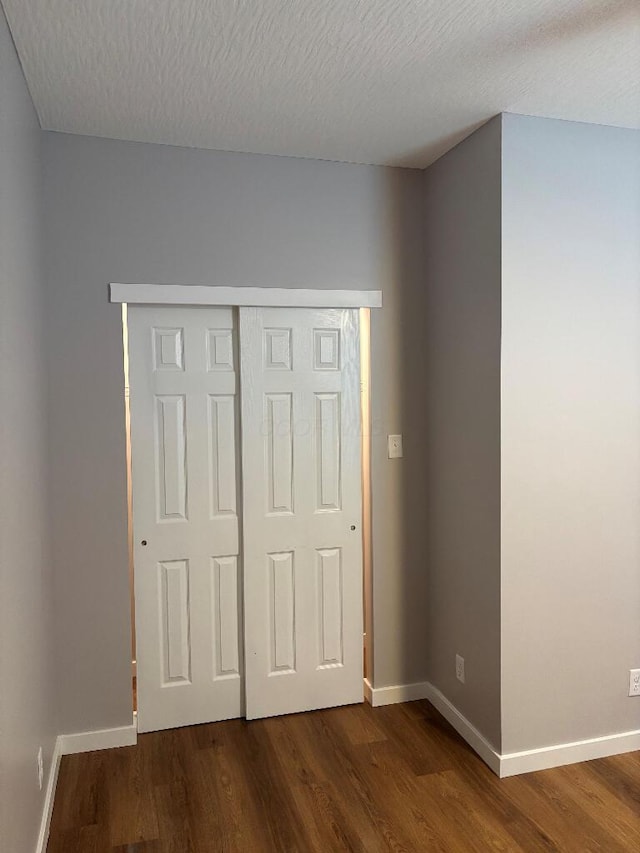 418 Clinton St, Circleville, OH 43113 - unfurnished bedroom featuring dark wood-type flooring, baseboards, a textured ceiling, and a closet