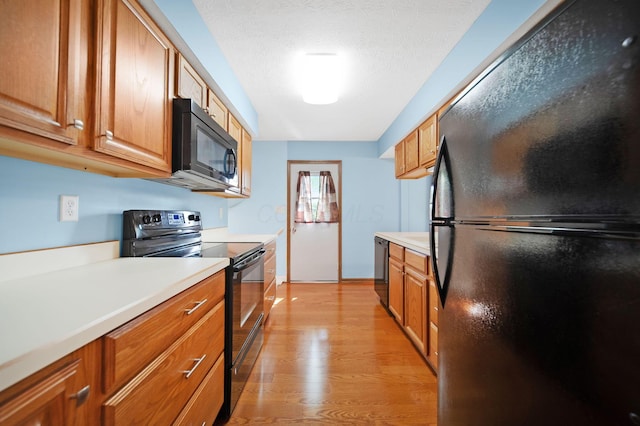 5770 Linworth Rd, Columbus, OH 43235 - kitchen featuring black appliances, light countertops, light wood-style flooring, brown cabinetry, and a textured ceiling
