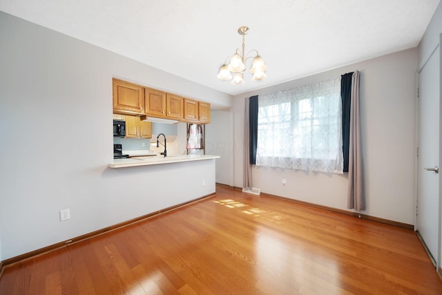 5770 Linworth Rd, Columbus, OH 43235 - kitchen with black microwave, a chandelier, light countertops, light wood-style floors, and stove