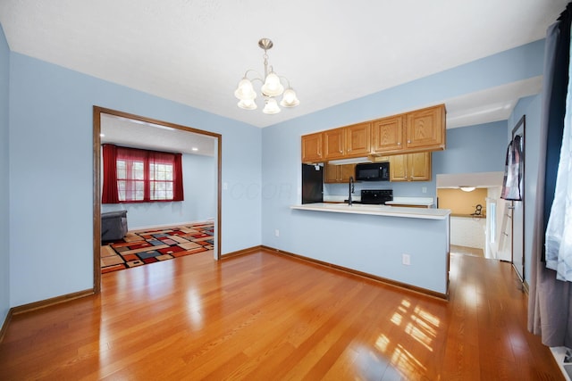 5770 Linworth Rd, Columbus, OH 43235 - kitchen featuring black appliances, a chandelier, light wood-style flooring, and light countertops