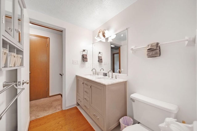 5770 Linworth Rd, Columbus, OH 43235 - bathroom featuring toilet, double vanity, wood finished floors, a textured ceiling, and baseboards