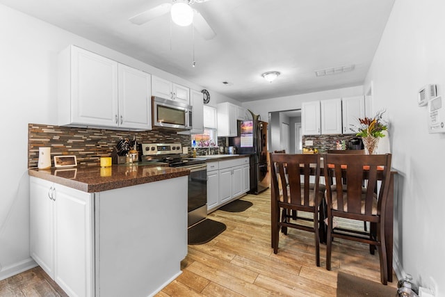 3009 Hiawatha St, Columbus, OH 43224 - kitchen with stainless steel appliances, decorative backsplash, white cabinets, dark countertops, and a ceiling fan