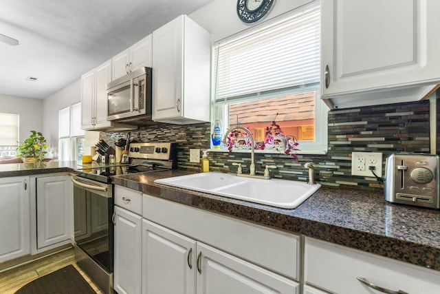 3009 Hiawatha St, Columbus, OH 43224 - kitchen featuring appliances with stainless steel finishes, a sink, dark countertops, and decorative backsplash