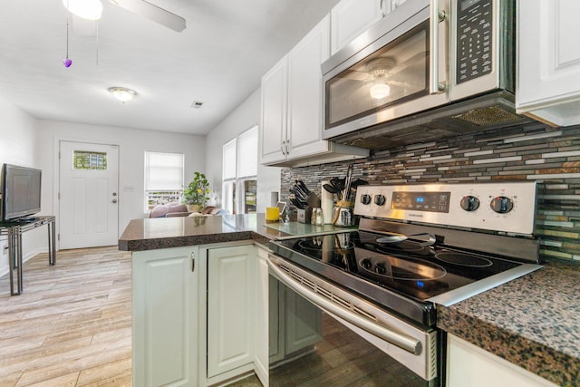 3009 Hiawatha St, Columbus, OH 43224 - kitchen with appliances with stainless steel finishes, light wood-style flooring, a peninsula, white cabinets, and dark countertops