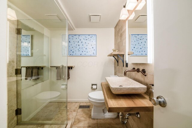 584 Franklin Ave, Columbus, OH 43215 - bathroom with toilet, a sink, a stall shower, tile patterned floors, and baseboards