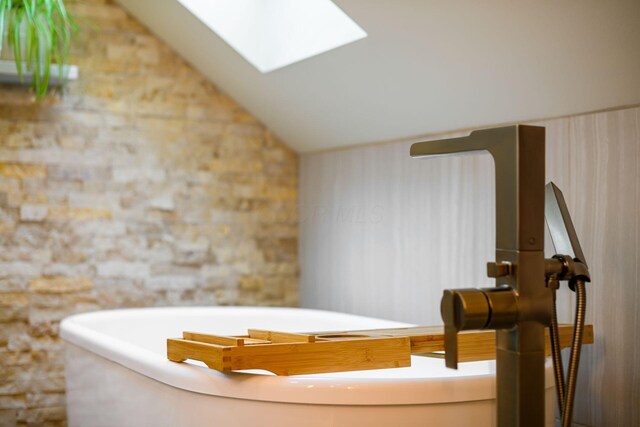 584 Franklin Ave, Columbus, OH 43215 - bathroom featuring a soaking tub, vaulted ceiling, and a skylight