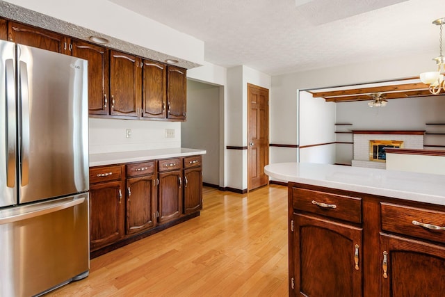 13582 Capetown Ave, Pickerington, OH 43147 - kitchen with freestanding refrigerator, light wood finished floors, light countertops, a brick fireplace, and decorative light fixtures