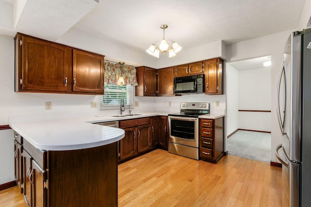 13582 Capetown Ave, Pickerington, OH 43147 - kitchen with appliances with stainless steel finishes, a peninsula, a chandelier, light wood-style floors, and light countertops