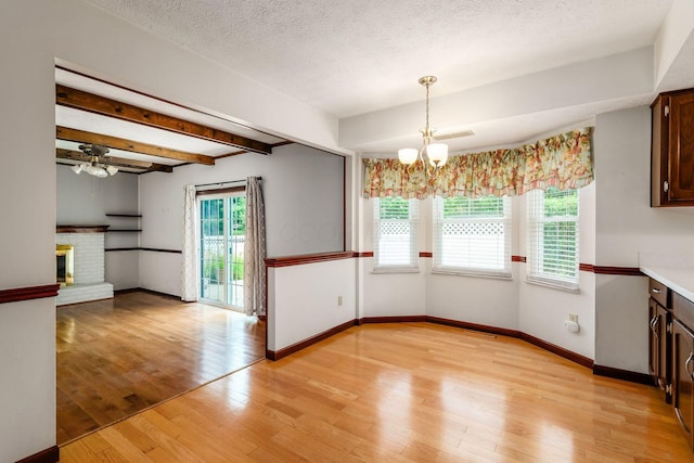 13582 Capetown Ave, Pickerington, OH 43147 - unfurnished dining area with a chandelier, light wood-style flooring, a fireplace, a ceiling fan, and a textured ceiling