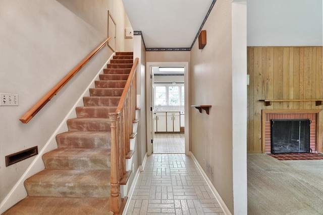 4399 Colerain Ave, Columbus, OH 43214 - stairway featuring brick flooring, wood walls, a brick fireplace, and baseboards