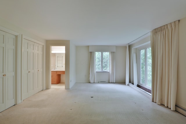4399 Colerain Ave, Columbus, OH 43214 - unfurnished bedroom with two closets, carpet floors, connected bathroom, and a baseboard heating unit