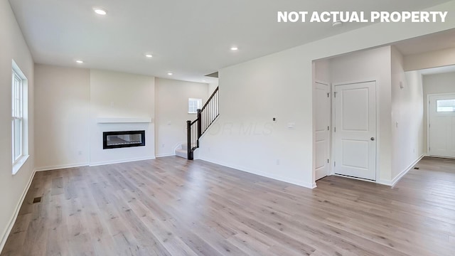 1486 Chrisman Dr, Columbus, OH 43223 - unfurnished living room featuring light wood-style flooring, stairway, baseboards, recessed lighting, and a glass covered fireplace