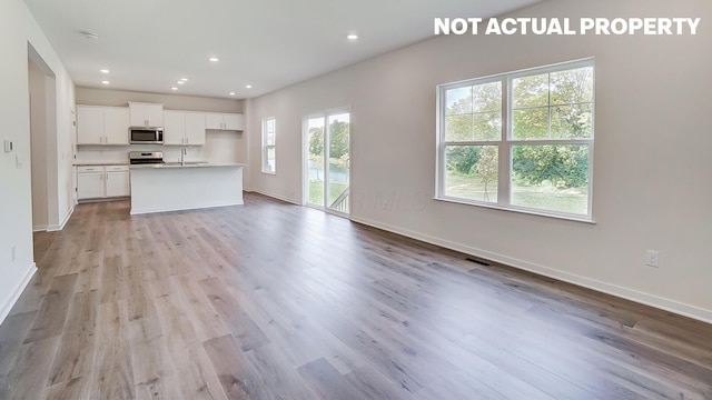 1486 Chrisman Dr, Columbus, OH 43223 - kitchen featuring stainless steel microwave, open floor plan, light wood-style flooring, baseboards, and recessed lighting
