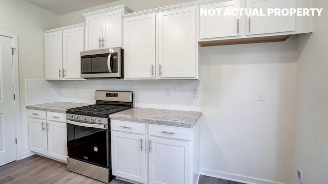 1486 Chrisman Dr, Columbus, OH 43223 - kitchen with appliances with stainless steel finishes, light wood-type flooring, tasteful backsplash, and white cabinets