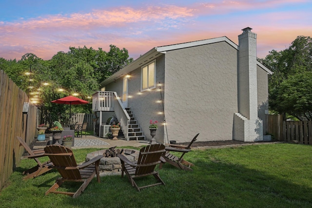 4561 Valley Quail Blvd N, Westerville, OH 43081 - back of house at dusk with an outdoor fire pit, stucco siding, a chimney, stairs, and a patio
