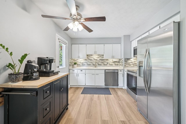 4561 Valley Quail Blvd N, Westerville, OH 43081 - kitchen featuring appliances with stainless steel finishes, white cabinets, decorative backsplash, light wood finished floors, and a sink