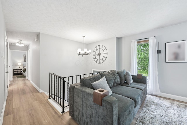 4561 Valley Quail Blvd N, Westerville, OH 43081 - living room with a chandelier, light wood-style floors, baseboards, and a textured ceiling