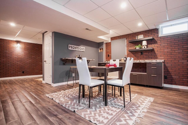 1808 Primrose Ave, Lewis Center, OH 43035 - dining space featuring brick wall, a paneled ceiling, baseboards, and light wood-type flooring