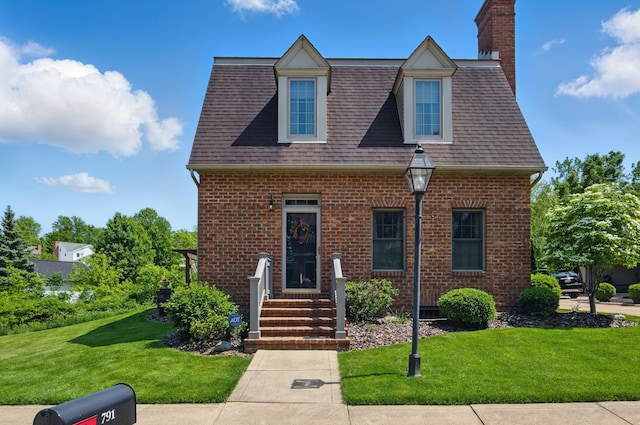 791 York St W, Mansfield, OH 44904 - view of front of house with a front yard, brick siding, a chimney, and a shingled roof