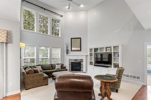 345 Quarter Way, Delaware, OH 43015 - living area with a towering ceiling, light wood-type flooring, a ceiling fan, baseboards, and a stone fireplace