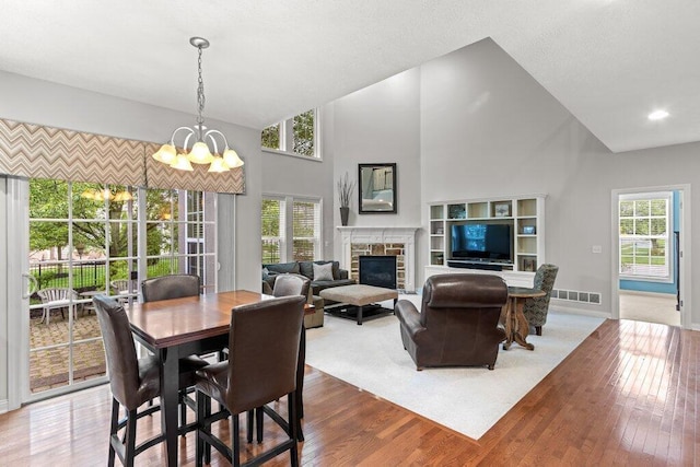 345 Quarter Way, Delaware, OH 43015 - dining area featuring a stone fireplace, wood finished floors, a chandelier, high vaulted ceiling, and baseboards