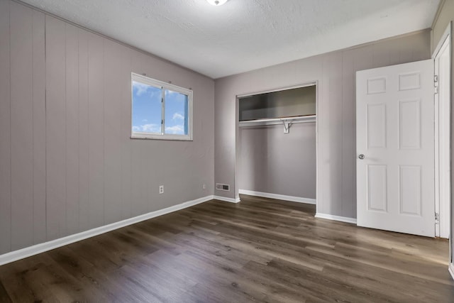 2872 Howey Rd, Columbus, OH 43224 - unfurnished bedroom with dark wood-type flooring, baseboards, a closet, and a textured ceiling