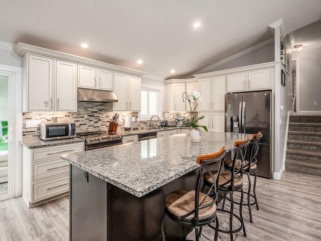 2073 Jeffey Dr, Hilliard, OH 43026 - kitchen with appliances with stainless steel finishes, ornamental molding, under cabinet range hood, a center island, and backsplash