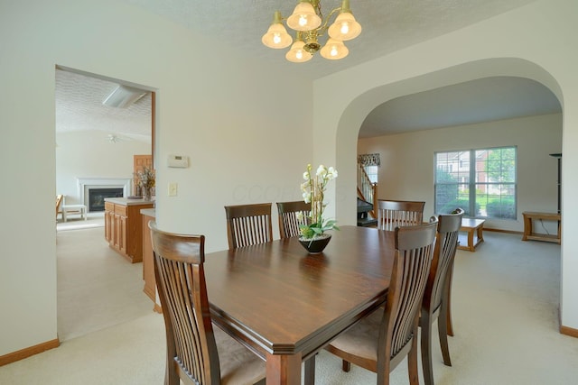1300 Sotherby Xing, Lewis Center, OH 43035 - dining room featuring arched walkways, light colored carpet, a chandelier, a textured ceiling, and a glass covered fireplace