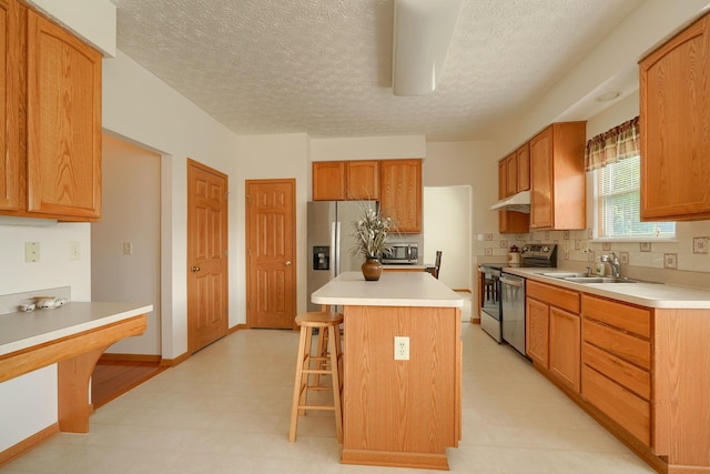 1300 Sotherby Xing, Lewis Center, OH 43035 - kitchen featuring stainless steel appliances, a sink, a breakfast bar area, light flooring, and under cabinet range hood