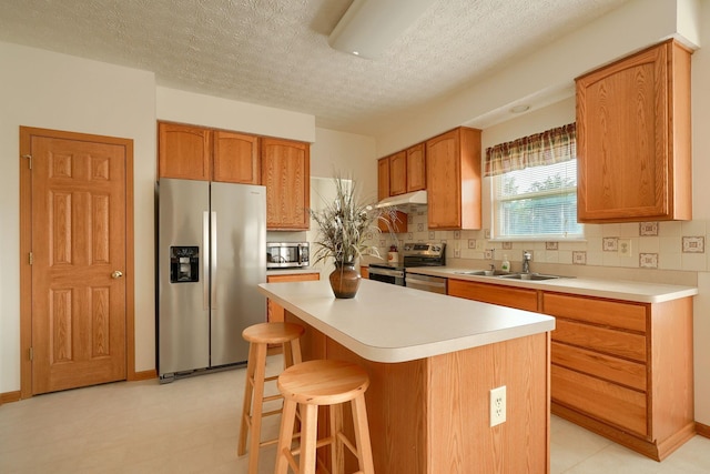 1300 Sotherby Xing, Lewis Center, OH 43035 - kitchen featuring stainless steel appliances, a sink, backsplash, a center island, and a textured ceiling