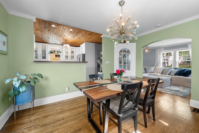 472 Tibet Rd, Columbus, OH 43202 - dining area featuring a chandelier, arched walkways, wood finished floors, baseboards, and crown molding