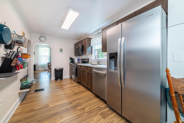 77 W High St, Mount Gilead, OH 43338 - kitchen with stainless steel appliances, light wood-type flooring, arched walkways, and dark brown cabinetry