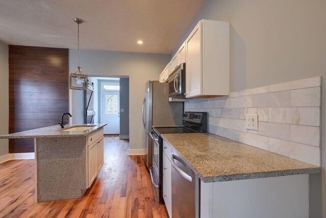 909-915 Wilson Ave, Columbus, OH 43206 - kitchen with a sink, stainless steel appliances, an island with sink, backsplash, and baseboards
