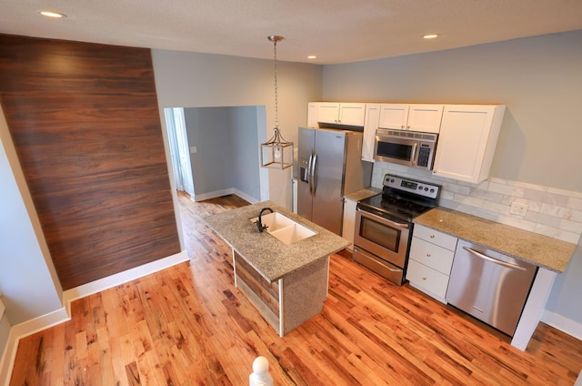 909-915 Wilson Ave, Columbus, OH 43206 - kitchen featuring stainless steel appliances, a sink, white cabinetry, decorative backsplash, and light wood-style flooring