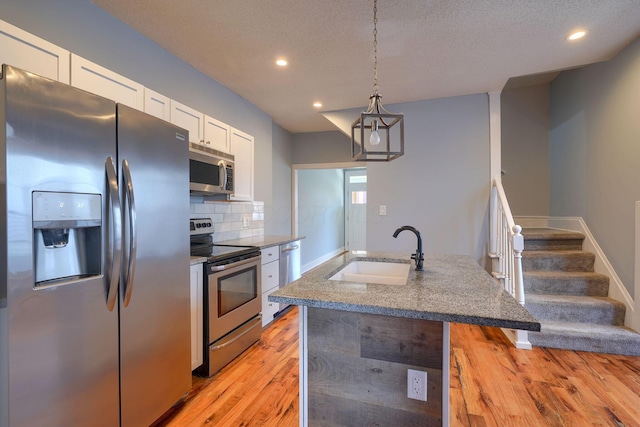 909-915 Wilson Ave, Columbus, OH 43206 - kitchen with appliances with stainless steel finishes, a sink, white cabinets, light wood-style flooring, and decorative backsplash