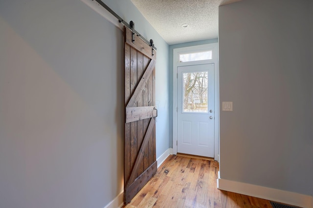 909-915 Wilson Ave, Columbus, OH 43206 - doorway with a barn door, a textured ceiling, light wood-type flooring, and baseboards