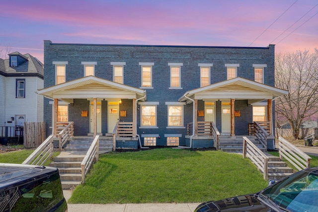 909-915 Wilson Ave, Columbus, OH 43206 - townhome / multi-family property with covered porch, brick siding, a yard, and stairway