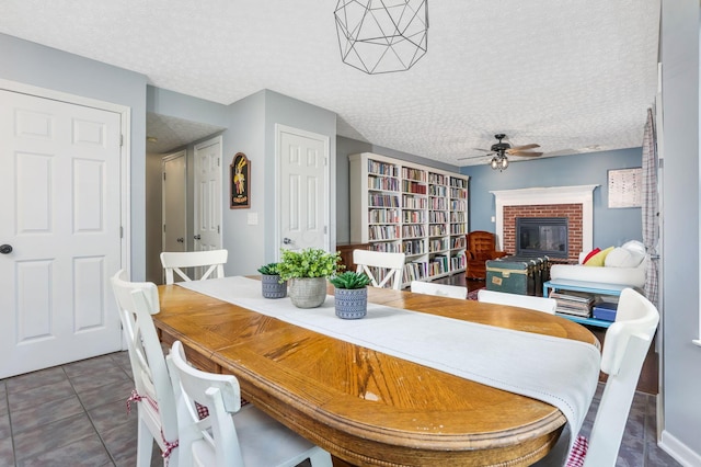 302 Streamwater Ct, Blacklick, OH 43004 - dining room with ceiling fan, a brick fireplace, a textured ceiling, and tile patterned flooring