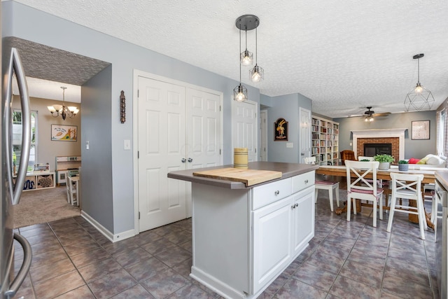 302 Streamwater Ct, Blacklick, OH 43004 - kitchen with butcher block counters, a brick fireplace, a textured ceiling, ceiling fan, and white cabinets