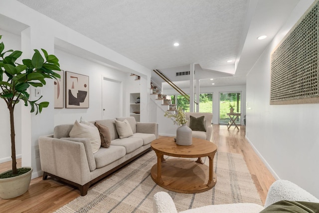 8121 Blind Brook Ct, Columbus, OH 43235 - living room featuring light wood-style flooring, stairs, recessed lighting, and a textured ceiling