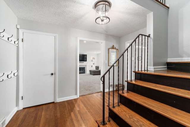 128 S Kellner Rd, Columbus, OH 43209 - stairway with a fireplace, wood finished floors, a textured ceiling, and baseboards