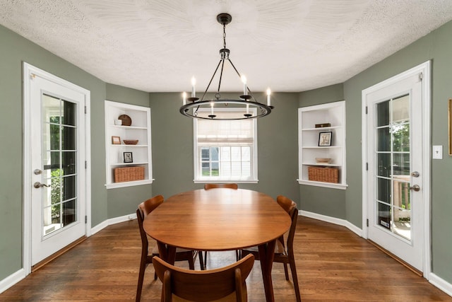 128 S Kellner Rd, Columbus, OH 43209 - dining space featuring built in features, a chandelier, dark wood-style flooring, a textured ceiling, and baseboards
