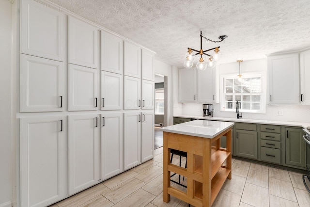 128 S Kellner Rd, Columbus, OH 43209 - kitchen with light countertops, a textured ceiling, a chandelier, white cabinetry, and decorative light fixtures