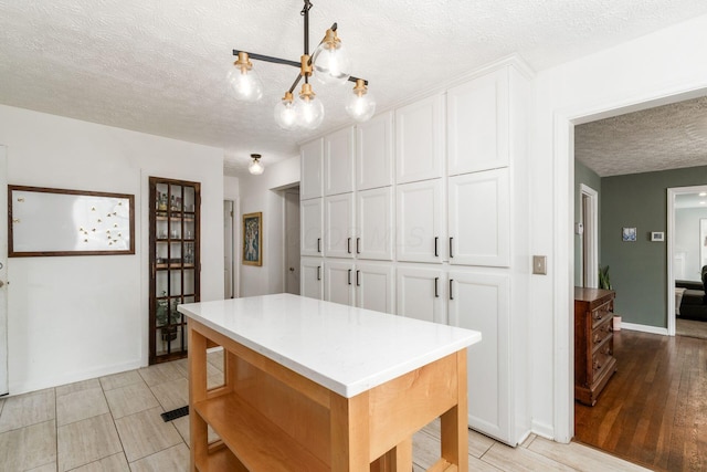 128 S Kellner Rd, Columbus, OH 43209 - kitchen featuring a textured ceiling, white cabinetry, a chandelier, light countertops, and a kitchen island
