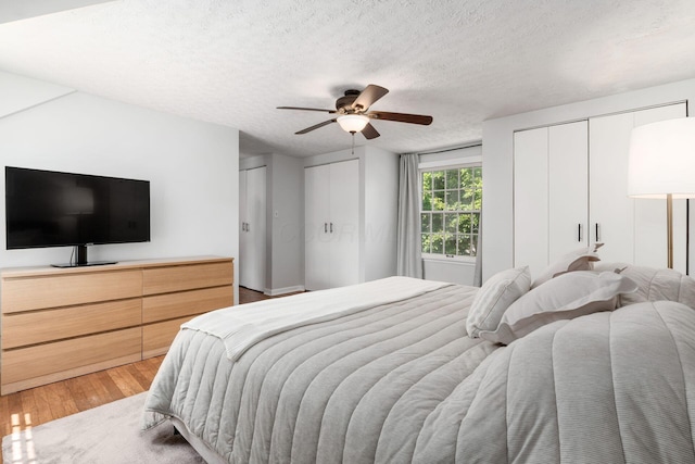 128 S Kellner Rd, Columbus, OH 43209 - bedroom featuring two closets, light wood-style floors, a textured ceiling, and a ceiling fan