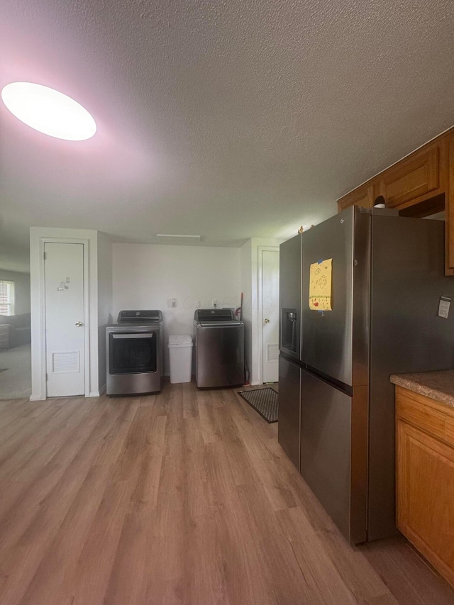 53 State St, Jeffersonville, OH 43128 - kitchen featuring stainless steel fridge, light wood finished floors, brown cabinets, a textured ceiling, and open floor plan